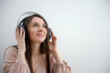 Young girl wearing headphones and listening to music Happy girl with headphones listens to music on a white background. High quality photo