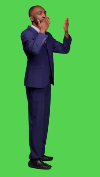 Vertical video: Profile of cheerful romantic office worker sending air kisses posing over full body green screen backdrop, doing optimistic gesture. Young man in formal suit with kissy face being