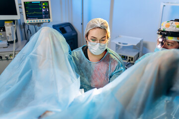 Professional female surgeon proctologist performing operation using special medical devices in the operating room in hospital. Urgent surgical concept