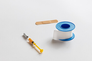 Patches spread on a white background next to which lies an anti-clotting syringe. The medical concept of fraying and the development of medicine.