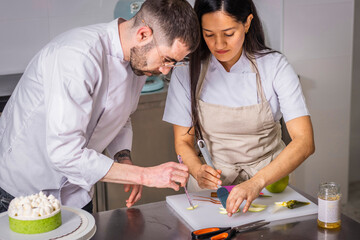 A couple of pastry chefs prepare and decorate a cake in pairs