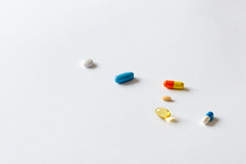 Scattered pills of different colors on a white background. 
Medical concept as pill addiction. A pill as a solution for everything.