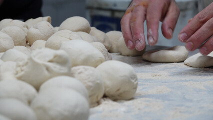 Fototapeta na wymiar male chef in the kitchen is preparing dough balls with his hands, close up view. Lahmacun making