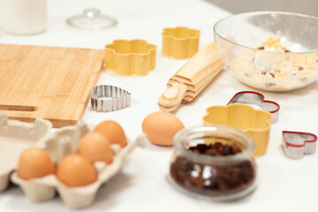 Dough for cookies with flour, butter and eggs, wooden rolling pin on table in kitchen interior, close up