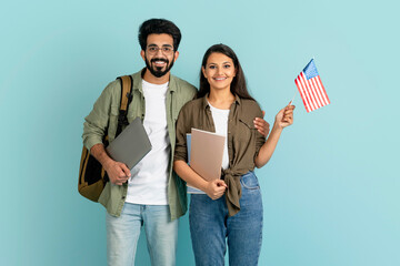 Cheerful multiethnic couple students showing flag of US