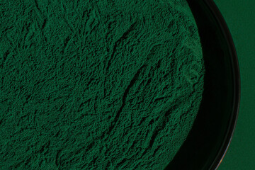 Fresh spirulina algae powder on green background, close-up, organic spirulina powder