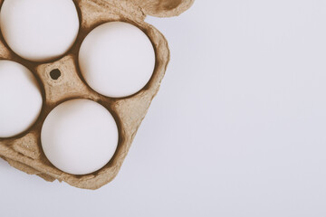 White eggs in brown egg tray on bright background. Selective focus. Concept scene. Top view. 