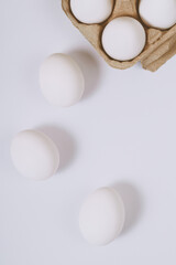 White eggs on bright background and in brown egg tray. Selective focus. Concept scene. Top view. 