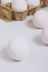 White eggs on bright background and in brown egg tray. Selective focus. Concept scene.