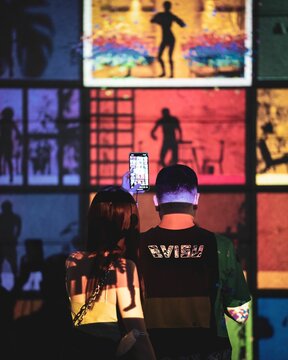 Vertical shot of a couple taking photos of light art installations in Singapore