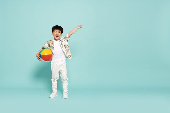 Asian little boy in flower pattern summer outfits holding beach ball  isolated on green background, Five years old