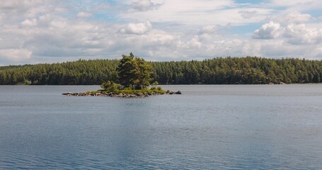 Scenic view of a small island with trees in the middle of a lake on a sunny day