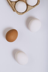 White and brown eggs on bright background and white eggs in brown egg tray. Selective focus. Concept scene. Top view. 