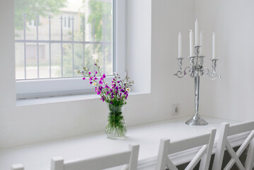a bouquet of wildflowers stands on a table in a vase in a white interior