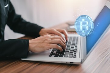 Bitcoin symbol and network signs in the air with a hand typing on a computer in the background