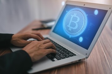 Man typing on a laptop with a bitcoin symbol on the screen, close-up