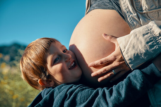 Ni&ntilde;o abrazando el vientre de su madre embarazada