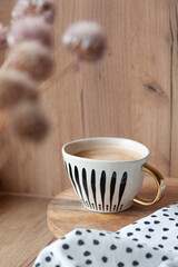 Modern cup of coffee and dries flowers on the wooden table, stylish home decorations, cozy small kitchen