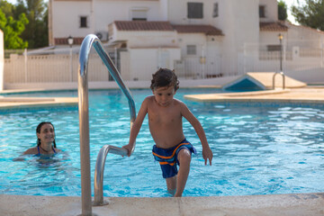 Naklejka premium child climbing out of the pool by the stairs