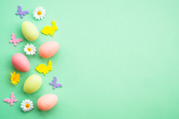 Happy Easter background with colored eggs and butterflies. Flat lay image at green.