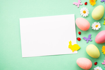 Easter background. Eggs, rabbit, spring flowers and butterfly. Flat lay mock up at green background.