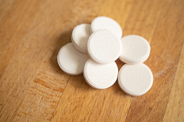 Fototapeta na wymiar large, round white tablets lie on a wooden table surface. Flu and cold season, new virus strain. Lack of vitamins in autumn, spring and winter, uncontrolled medication