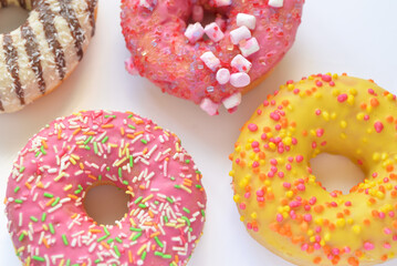 A group of pink, yellow and chocolate donuts with sprinkles on white background