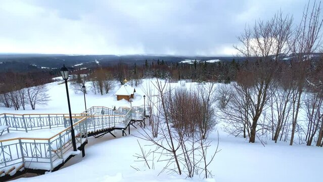 View of the chapel near the Belogorsky St. Nicholas Orthodox Missionary Monastery. Winter forest. The temple on the hill in winter. Russia, Perm Krai, Belaya Gora. 4K
