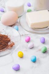 Ingredients for cooking. Eggs, cacao, piece of butter, flour, sugar, colorful candy eggs on table. Ingredients for making dough. Ingredients for baking cookies.