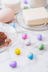 Ingredients for cooking. Eggs, cacao, piece of butter, flour, sugar, colorful candy eggs on table. Ingredients for making dough. Ingredients for baking cookies.