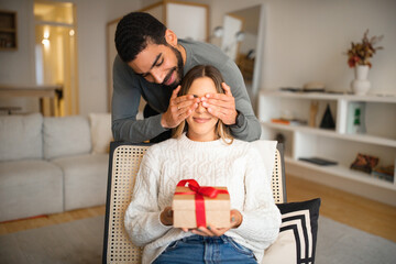Cheerful multiethnic millennial family celebrating birthday, anniversary, holiday, husband close eyes to wife