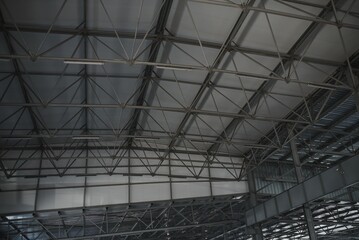 Steel roof structure for building construction. Metal roof structure of a building under construction on a blue sky background with white clouds. Selective focus
