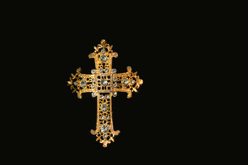 openwork decorated beautiful golden cross with rhinestones isolated on abstract black background...
