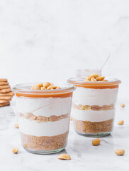 Cheesecake in a jar. Layers of grinded cookies, caramel, peanuts and  cream cheese. Covered in...