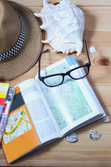 Leisure accessories. Hat, sea shell and travel guides on a wooden background. Top view with copy space - 583221136