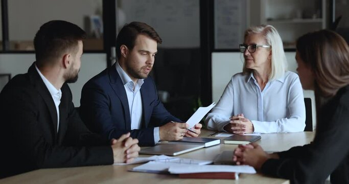Young and mature staff listening team leader, company boss make speech, reporting about sales results, strategy, corporate goals at group meeting in conference room. Negotiations, training, business