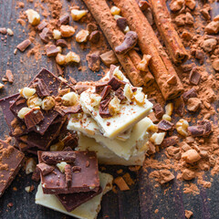 stack of chocolate with grated nuts and cocoa on a black background