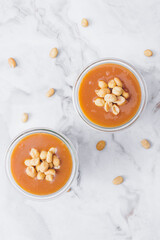 Glass jars with caramel, decorated with salty peanuts on table. Top view.