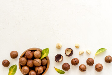 Shelled macadamia nuts in bowl with green leaves. Protein food