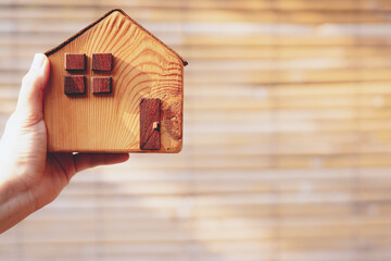 Obraz na płótnie Canvas House model in home insurance broker agent’s hand with building background. Real estate agent offer house, property insurance concepts.