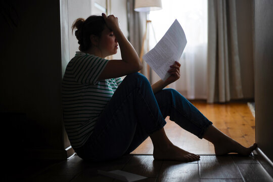 Silhouette of a sad woman sitting on the floor of her apartment