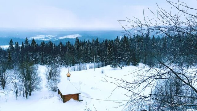 View of the chapel near the Belogorsky St. Nicholas Orthodox Missionary Monastery. Winter forest. The temple on the hill in winter. Russia, Perm Krai, Belaya Gora. 4K