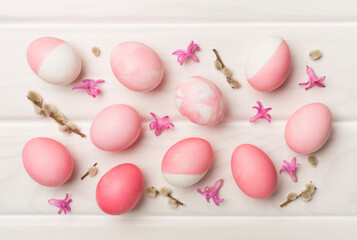 Pink Easter eggs with decor on wooden background, top view