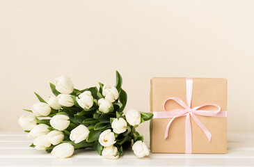 White tulip bouquet with gift box on table