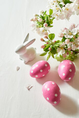 Holiday composition with spring flowers and easter eggs, white bunny on a light background. Happy easter concept with copy space