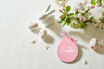 Holiday composition with spring flowers and easter eggs, white bunny on a light background.  Happy easter concept with copy space