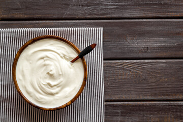 Sour cream or yogurt in wooden bowl. Dairy product background