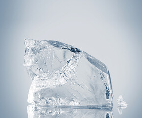 Natural crystal clear single ice piece on white background with reflection.