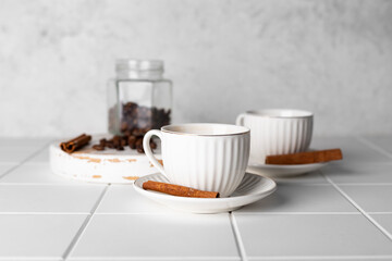 Close-up of a coffe cups, coffee beans and cinnamon sticks on a white background.
