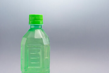Closeup Green Ribbed Plastic Bottle With Liquid, Juice On Grey Background. Copy space for text, horizontal plane